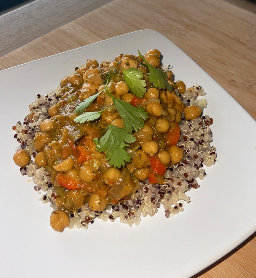 Plate of chickpea vegetable curry served on a bed of quinoa topped with coriander