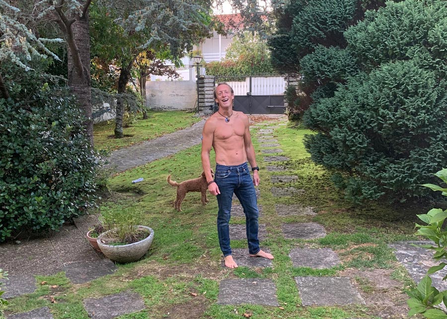 Chris in good shape with his top off in a lovely green garden