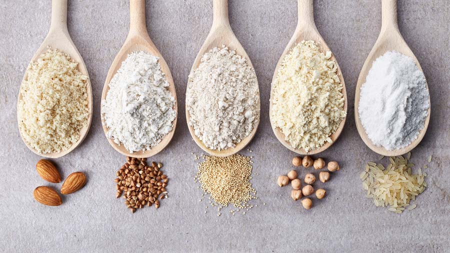 5 wooden spoons with non-gluten flours: almonds & almond flour, chickpeas & chickpea flour, rice & rice flour, plus grain & nut flours