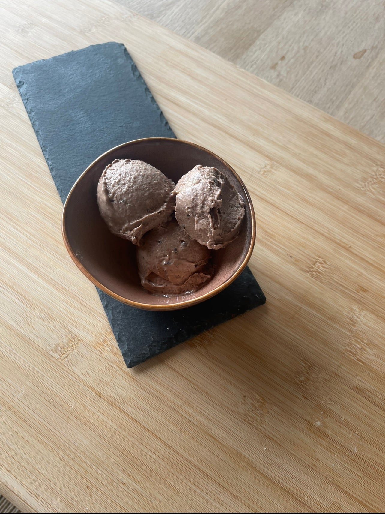3 scoops of vegan banana & chocolate ice cream in a rustic bowl on a serving slate