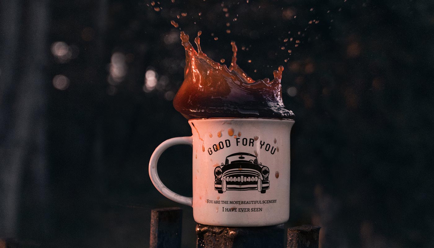 Rustic mug in natural rural woods with coffee spilling out from the top