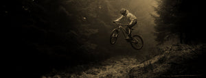 Off-road mountain bike rider jumping high on a trail in the woods