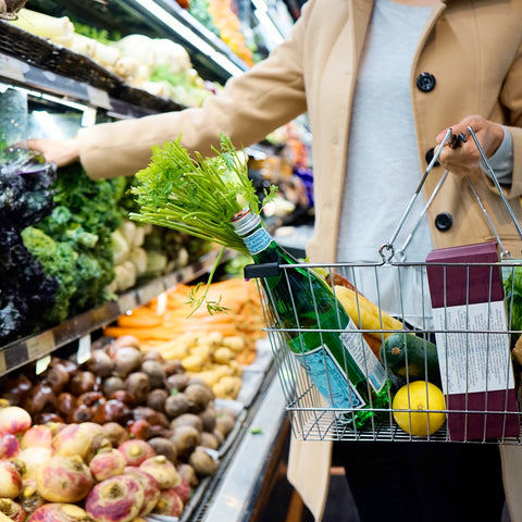 woman shopping with basket in the fresh vegetable aisle